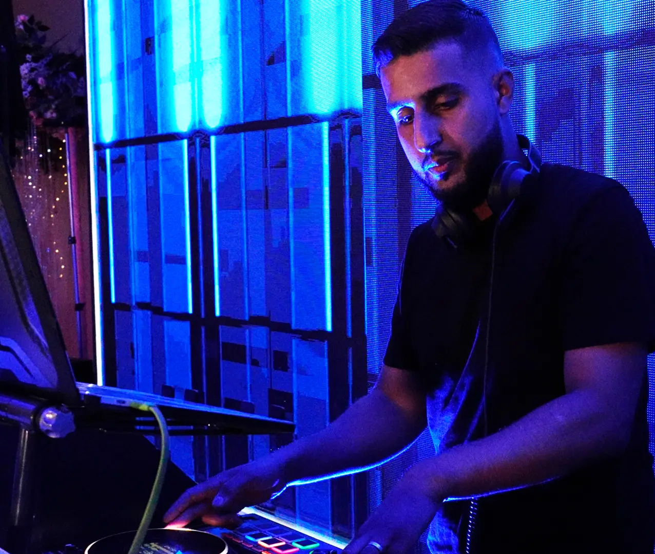 DJ mixes music at a vibrant event with blue lighting and headphones.