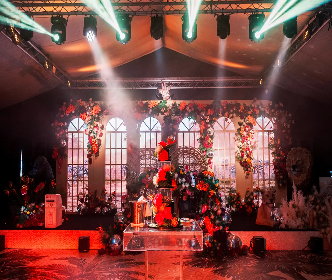 Vibrant event stage with floral decor, dramatic lighting, and jungle-themed backdrop, creating an exotic ambiance.